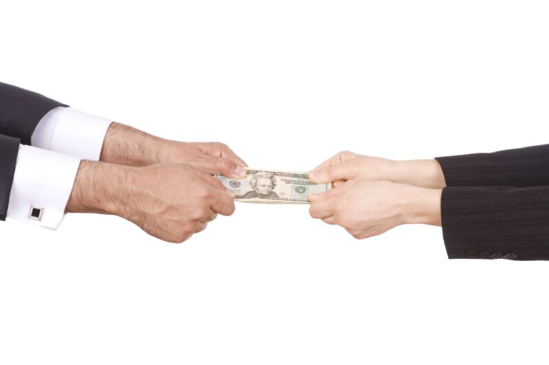 People fighting over money—image shows two people's hands pulling on either end of a stack of $20 bills.